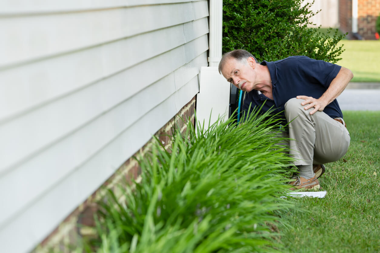 a man inspecting his house's foundation